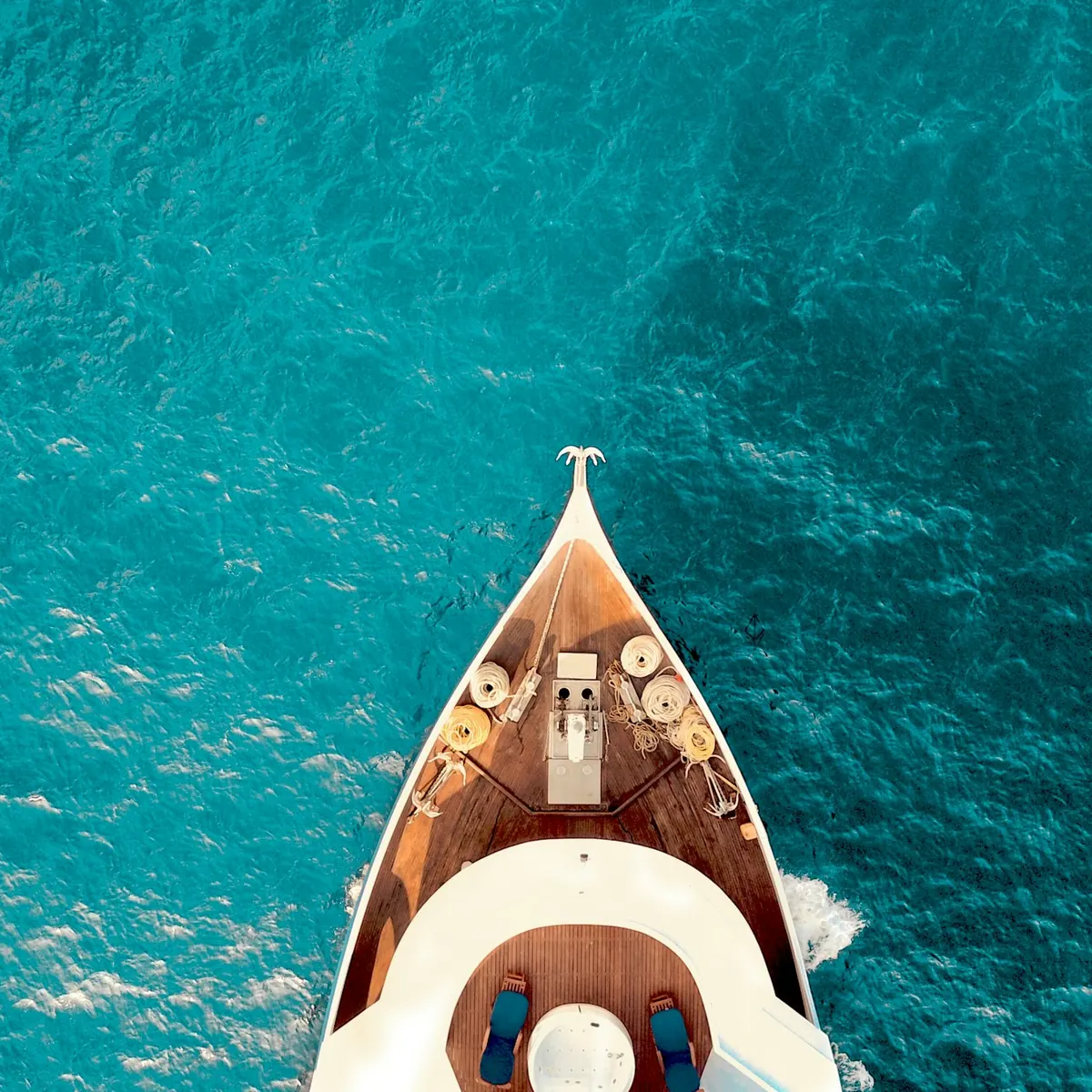 Bow of a yacht cutting through turquoise water